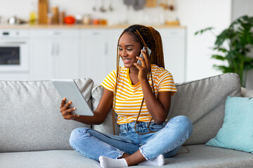Obraz premium Afro american woman freelancer talking on phone and using tablet