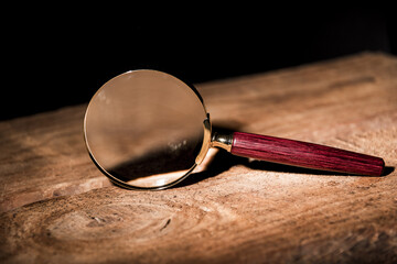 Fototapeta na wymiar Close up Single Magnifying Glass with Black Handle, Leaning on the Wooden Table at the Office.