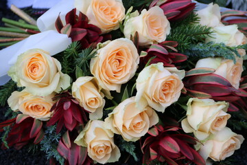 Blumenstrauss mit Rosen lachsfarben und Trauerflor auf dem Friedhof nach Beerdigung