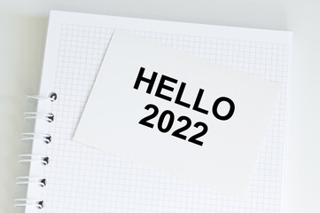 Hello 2022 text on white card on notepad, business plans