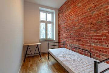 Bright, single, classic bedroom with a clean red brickwall.
