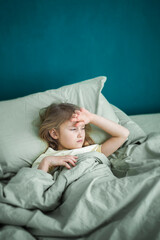 A little girl lies in bed and is sick, feeling unwell and having a cold in the winter