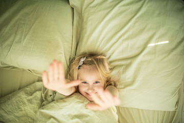 Little caucasian girl with blond hair sleeps in a soft bed of light green color