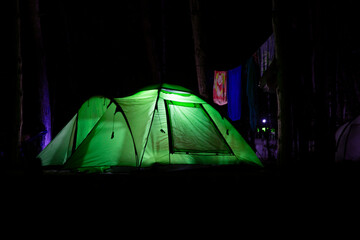 Illuminated tourist tent in the summer camp  at night. Glowing camping tent in the wood.