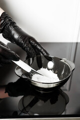 Female hands in medical gloves hold a bowl of white powder. Kaolin clay white powder cosmetic grade...