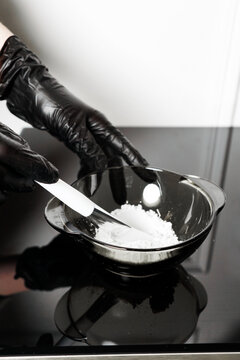 Female hands in medical gloves hold a bowl of white powder. Kaolin clay white powder cosmetic grade for face mask and spa treatments. Vertical photo