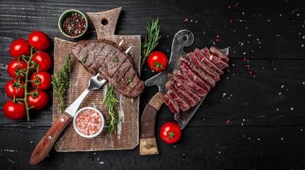 Grilled beef steak on a fork adding rosemary on black background. banner, menu, recipe place for text, top view