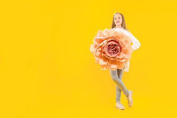 Beautiful bud. Girl holding a huge peony flower in her hands on a yellow background