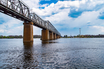 Concrete supports of the railway bridge over the river. Water crossing. Railway track. Bridge construction. Moving over water. Transport crossing. Dnepr River. Overcast sky. Industrial design.