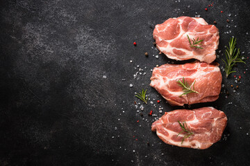 Raw meat. Fresh steaks with herbs and spices at black background. Top view.