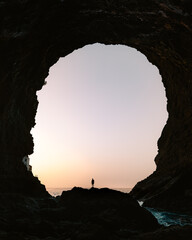 Silueta de un hombre joven debajo una gran cueva en Islas Canarias