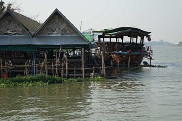Fototapeta na wymiar Stilt huts and boat on River Chao Phraya between Bangkok and Ayutthaya, Phatum Thani, Thailand
