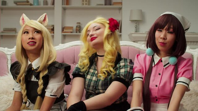 Cheerful attractive diverse multicultural women cosplayers in wigs and costumes, representing anime and comic book characters, talking and sharing with online audience about cosplay lifestyle.