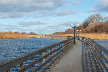 Wooden walkway through the lake. Winter lake, floating walkway and reeds in Yantarny, Kaliningrad oblast