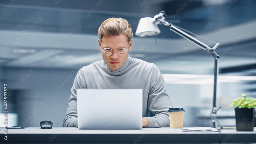 Poster modern office: productive businessman sitting at his desk working on a laptop computer. man working 