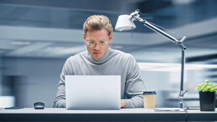 Modern Office: Productive Businessman Sitting at His Desk Working on a Laptop Computer. Man working...
