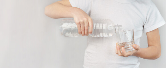 the boy pours drinking water into a glass.