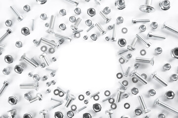 Frame of different metal bolts and nuts on white background, top view. Space for text