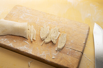 Cooking homemade noodles. Sliced strips of noodles from the formed dough lie on a wooden cutting board..