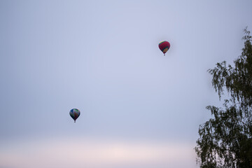 two balloons with baskets are flying high in the sky