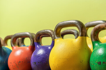 Naklejka na ściany i meble Old multicolored kettlebells against the wall in the gym.