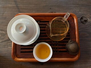 Tea ceremony in minimalism style, black puer tea in ceramics bowls,dry pu-erh tea leaves in a wooden bamboo spoons and plate on a beige background
