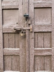 wooden painted door of brown color closed on two locks hanging