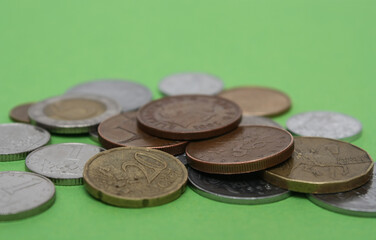 Coins of different countries. A scattering of coins on a green background. Shallow depth of field