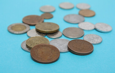 Coins of different countries. A scattering of coins on the blue background. Shallow depth of field, copy space