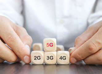 hand hold ing a wooden cube 5G network (5th generation) connects the technology of the future around the world. Wooden cubes switched to 5G