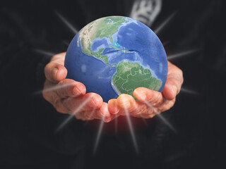Close-up of the Earth on the palm senior woman. Concept of saving the Earth, environment, and energy.