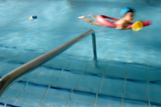 Artistic image of a little boy swimming with a float in an indoor pool