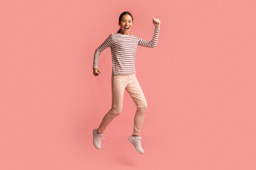Fototapeta na wymiar Excited Happy Young Asian Woman Celebrating Success While Jumping In Air