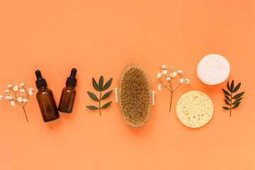 Fototapeta na wymiar Cleansing, moisturizing and massaging accessories on the light orange background. Oil and serum, massaging brush and cleansing cosmetic sponges. Beauty care products. 