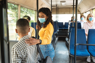 Fototapeta na wymiar Black lady wearing protective mask talking to son in bus