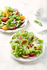 Salad with red and yellow Tomatoes and Pomegranate Seeds on bright wooden Background. Close up.