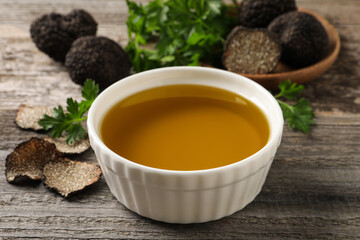 Fresh truffle oil in bowl on wooden table, closeup