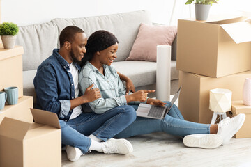 Online Order. Young black couple using laptop, purchasing furniture in internet