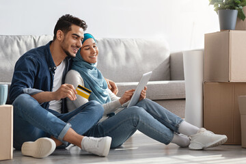 Happy arabic couple with digital tablet and credit card