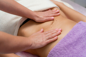 Fototapeta na wymiar Top view of hands massaging female abdomen.Therapist applying pressure on belly. Woman receiving massage at spa salon