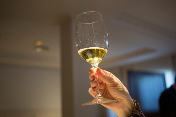 A hand holding a white wine in movement in a wineglass in first pane High quality photo