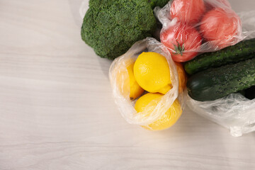 Plastic bags and fresh products on white table, flat lay. Space for text