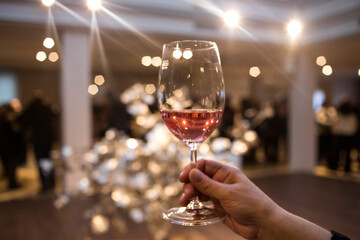 A hand holding a Rose wine in movement in a wineglass in first pane High quality photo