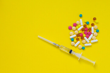 syringe and pills on yellow background