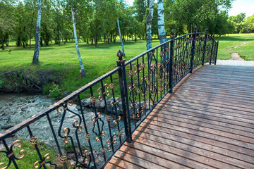 Footbridge over the brook . Wooden pedestrian bridge in the park . Walking in the springtime