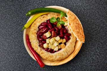Baked bean dish in bread crust. Mexican food with red beans, hot peppers, sausages and onions.