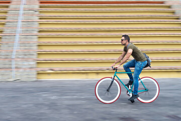 Man with sunglasses riding bicycle in urban city commuting trendy transportation