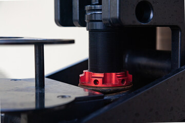 A steel mechanism with a threaded stem and a red clamping nut on it.