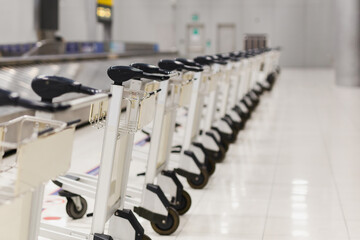 Fototapeta na wymiar Empty airport luggage carts parking behind warning line in baggage claim area in terminal.