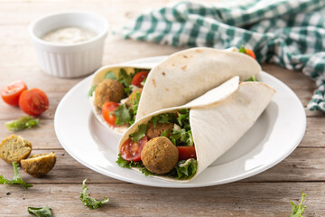 Tortilla wrap with falafel and vegetables on wooden table